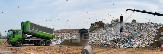 수도권매립지 제3-1매립지에 쓰레기가 쏟아지는 모습. 사진 오른쪽 상부에 찍힌 대롱에서 암모니아 탈취용액이 섞인 물이 쓰레기더미로 뿌려지면서 악취 확산을 막는다. 사진 이미연 기자
